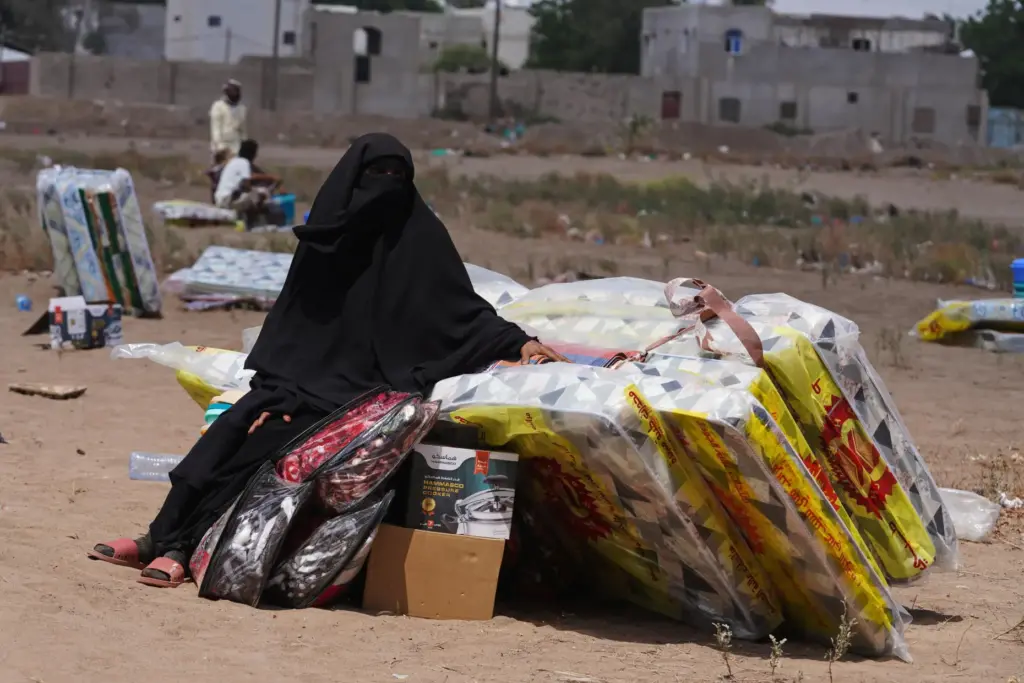 A displaced Yemeni woman sits beside mattresses distributed at the Al-Fallahine displacement camp.