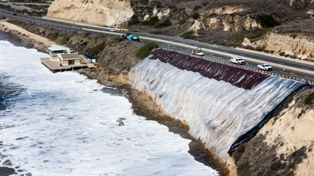 A tarp covers a crumbling bluff along Pacific Coast Highway...