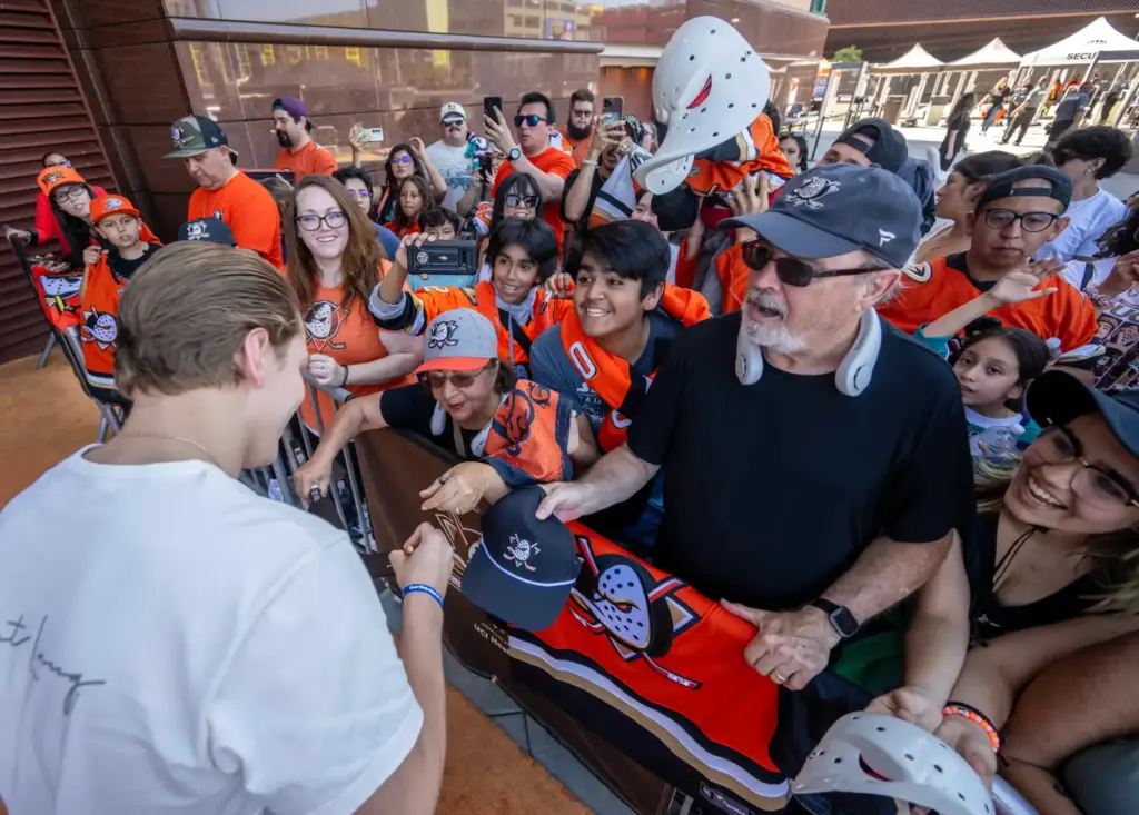 Ducks player Pavel Mintyukov signs an autograph on the orange...