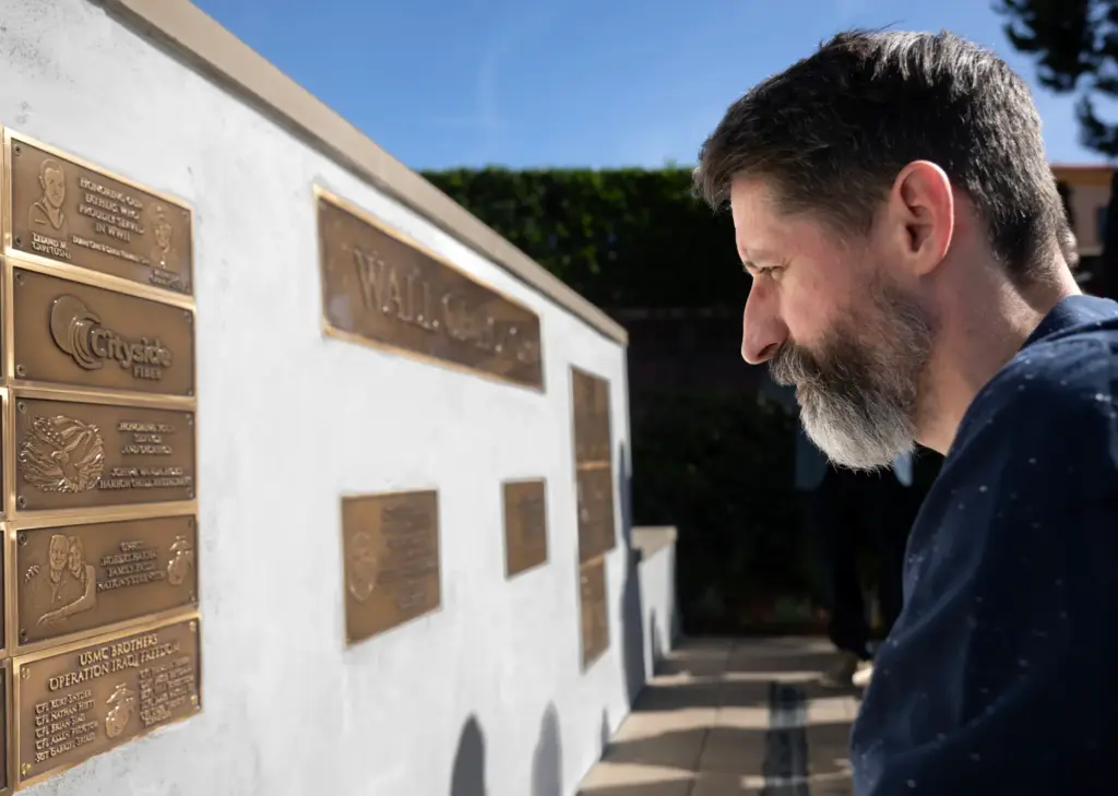 Marine veteran Kurt Snyder looks at a plaque his cousin...