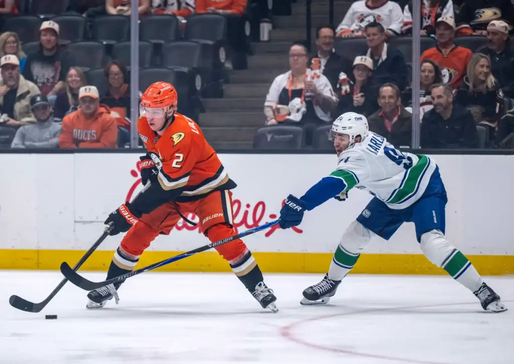 The Ducksâ Jackson LaCombe, left, controls the puck as the...