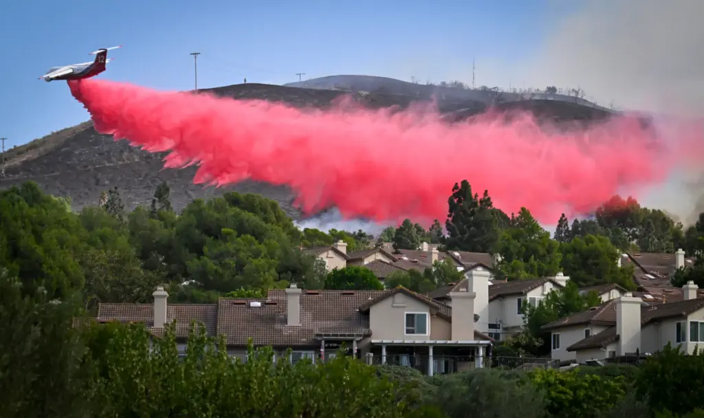 A fire retardent dropping aircraft works to save homes during...