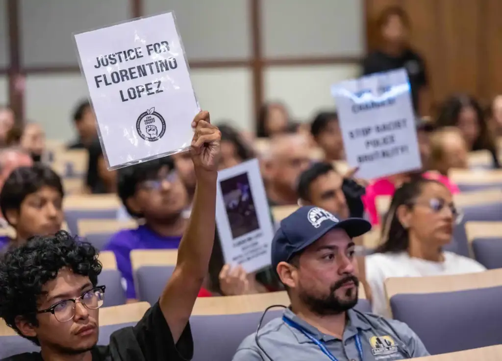 Members of the public hold up signs critical of the...