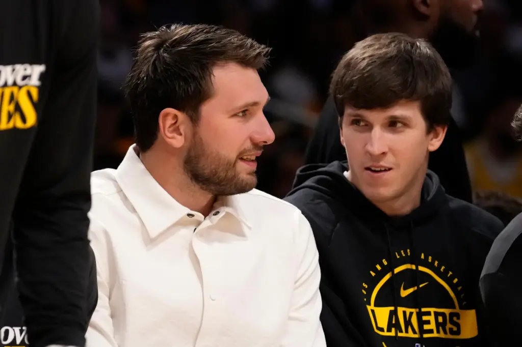 Injured Lakers guards Luka Doncic, left, and Austin Reaves chat...