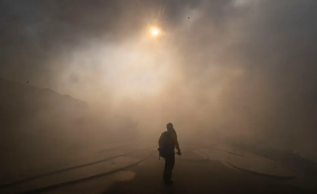 The sun is obscured as firefighters work to save structures...