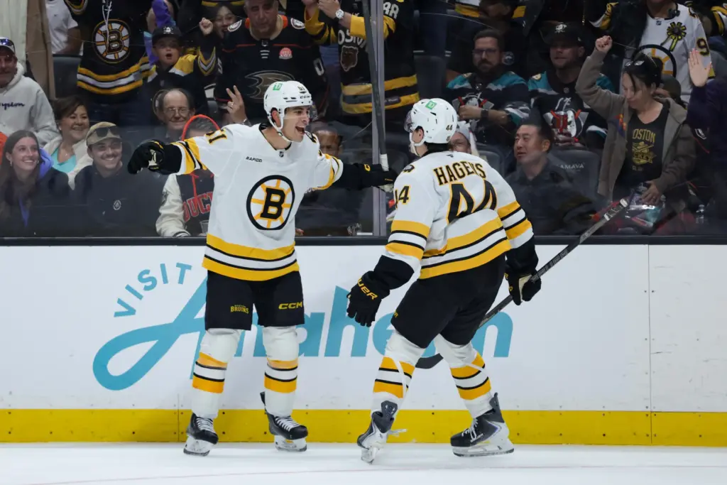 Boston Bruins center Matthew Poitras, left, celebrates with center James...