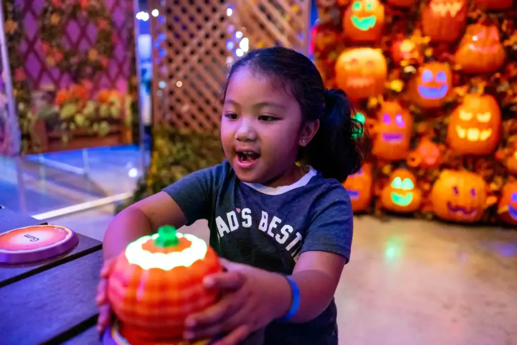 Luna Ryan places a toy pumpkin atop different pedestals to...