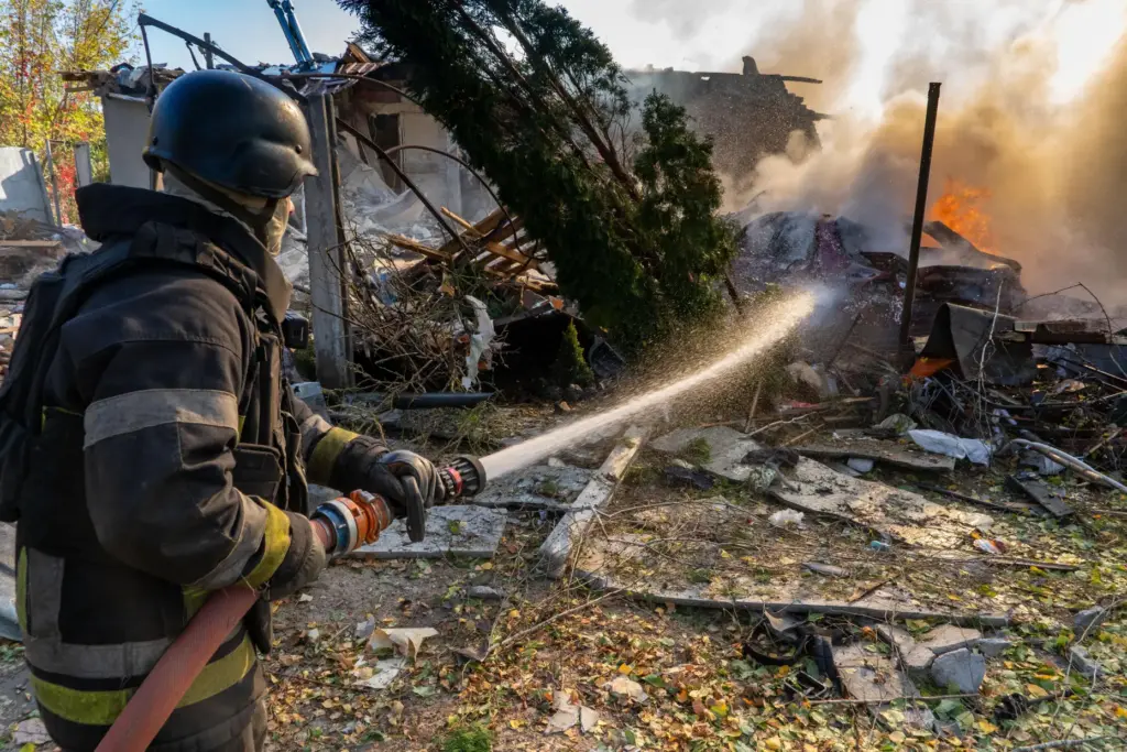 A rescue worker puts out a fire at residential houses destroyed in a Russian strike.