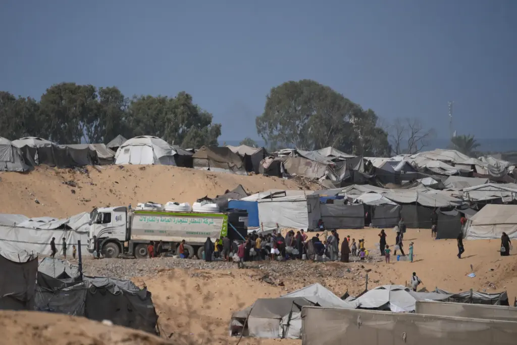 Displaced Palestinians gather to fill containers with fresh water.