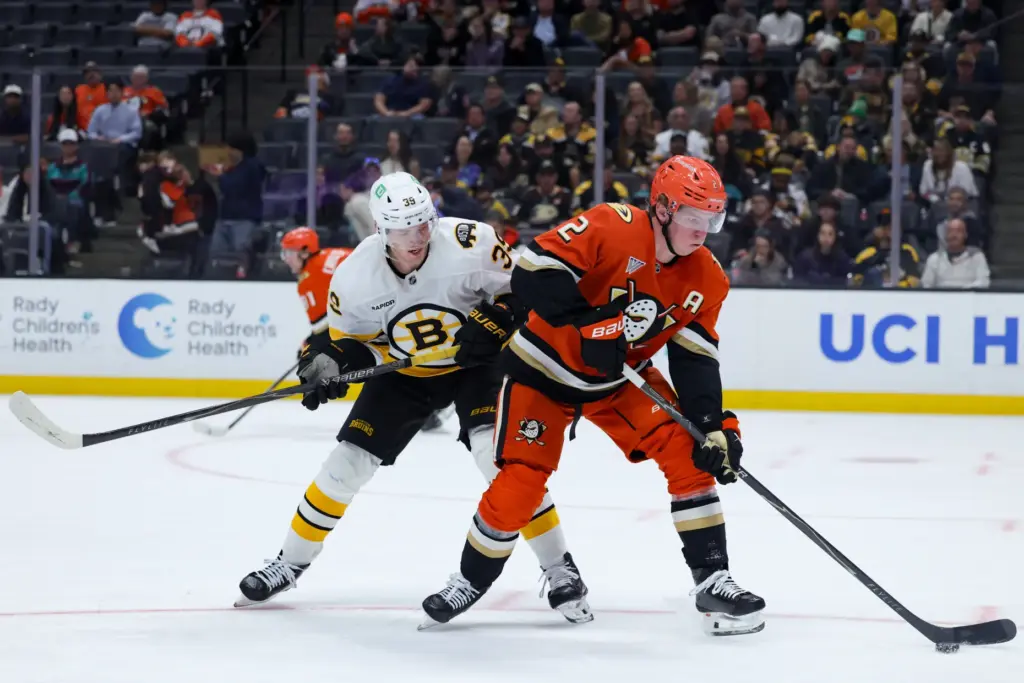 Ducks defenseman Jackson LaCombe, right, and Boston Bruins center Morgan...