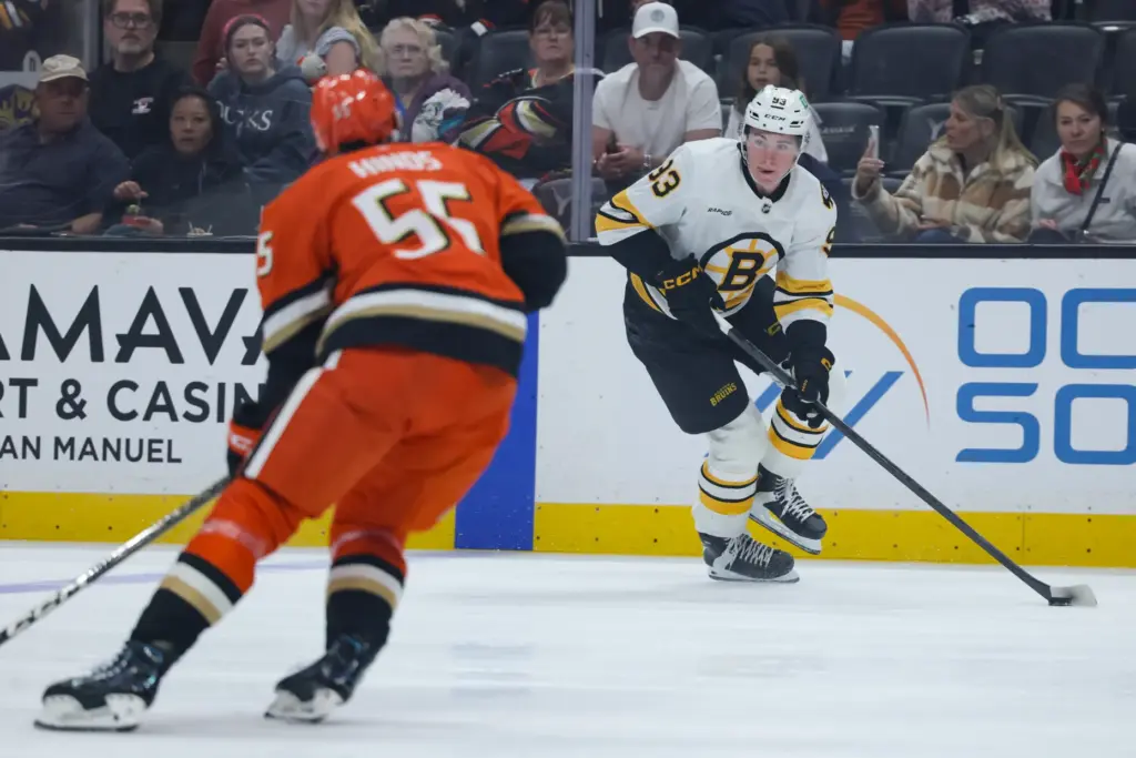 Boston Bruins center Fraser Minten, right, moves the puck ahead...