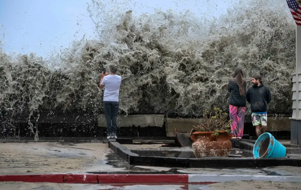 A wave crashes up and over a small retaining wall...