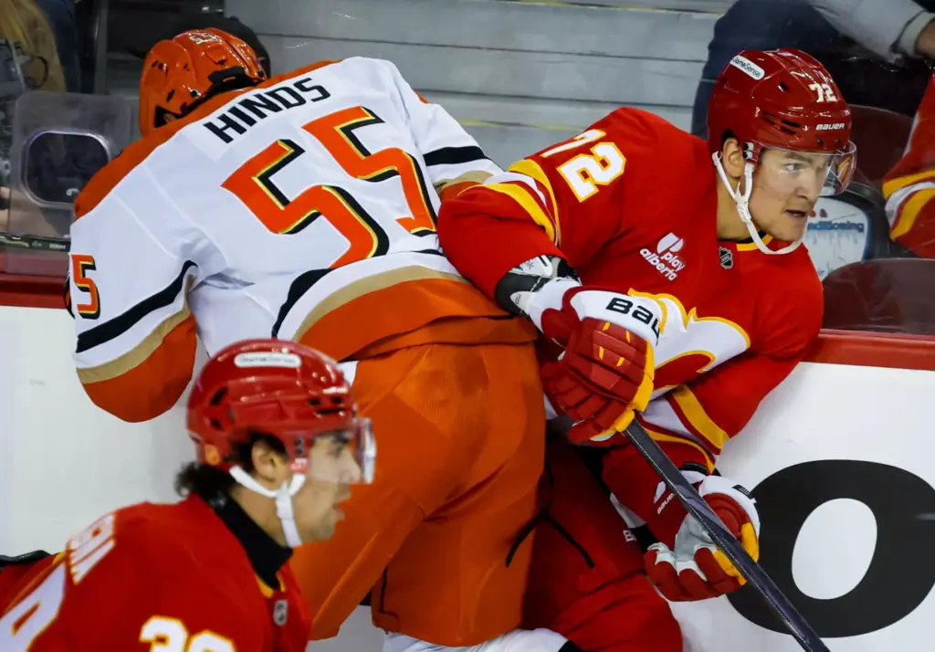 Ducks’ Tyson Hinds, left, checks Calgary Flames’ Maksim Tsyplakov during...