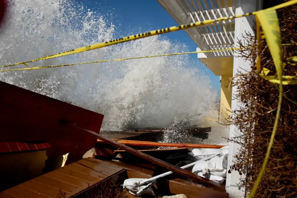 Waves continue to crash into homes and the heavily damaged...