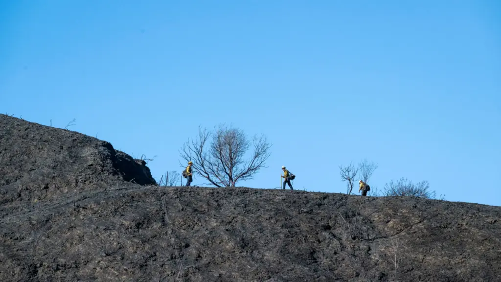 Firefighters work on a hillside near Via Cerro Rebal on...