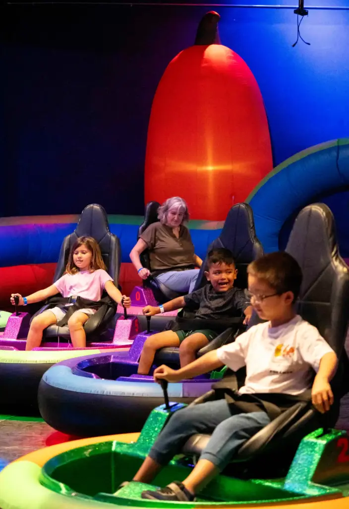 Attendees enjoy the bumper cars beneath a large blow up...