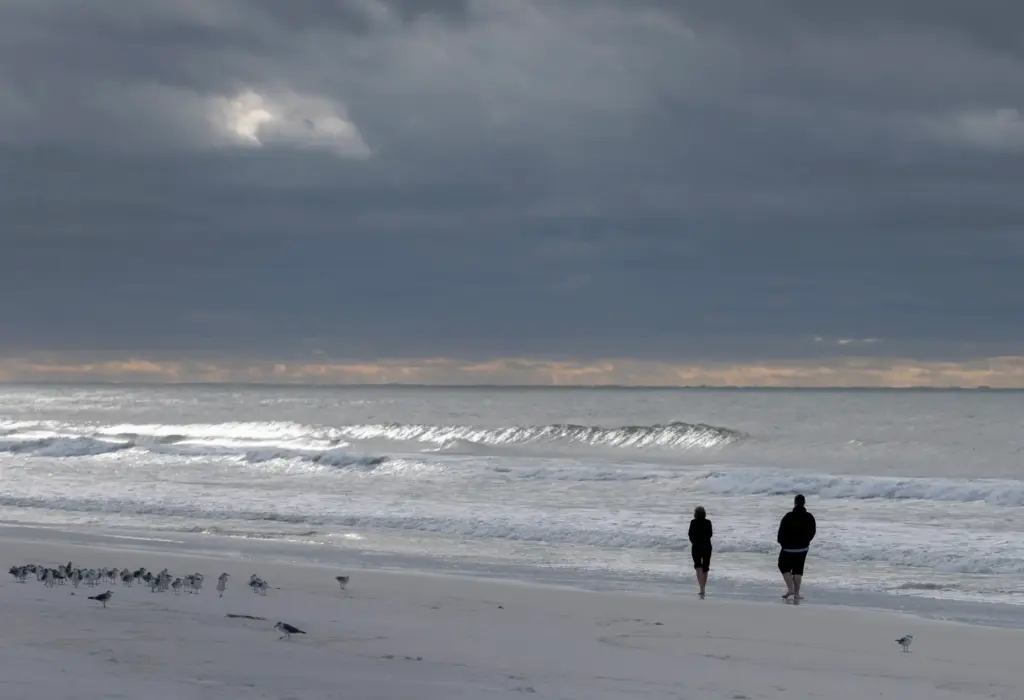 People walk along the beach after Hurricane Isaias passed through...