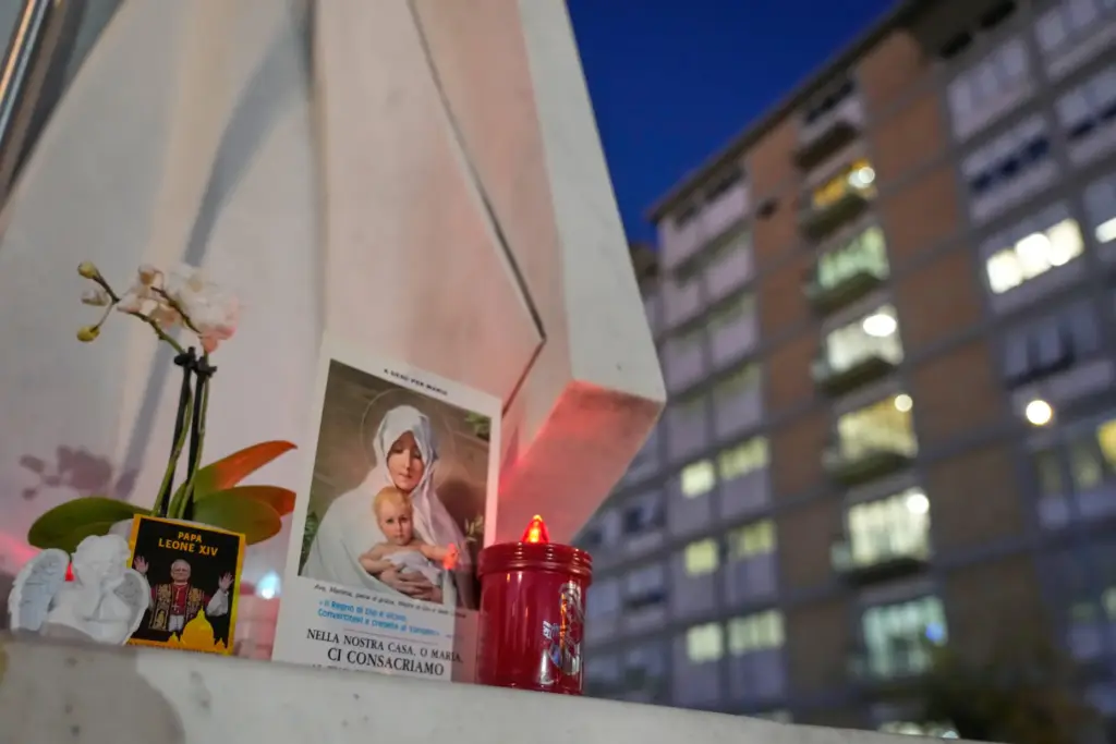 An image of Pope Leo rests on a statue of the Pope John Paul II.