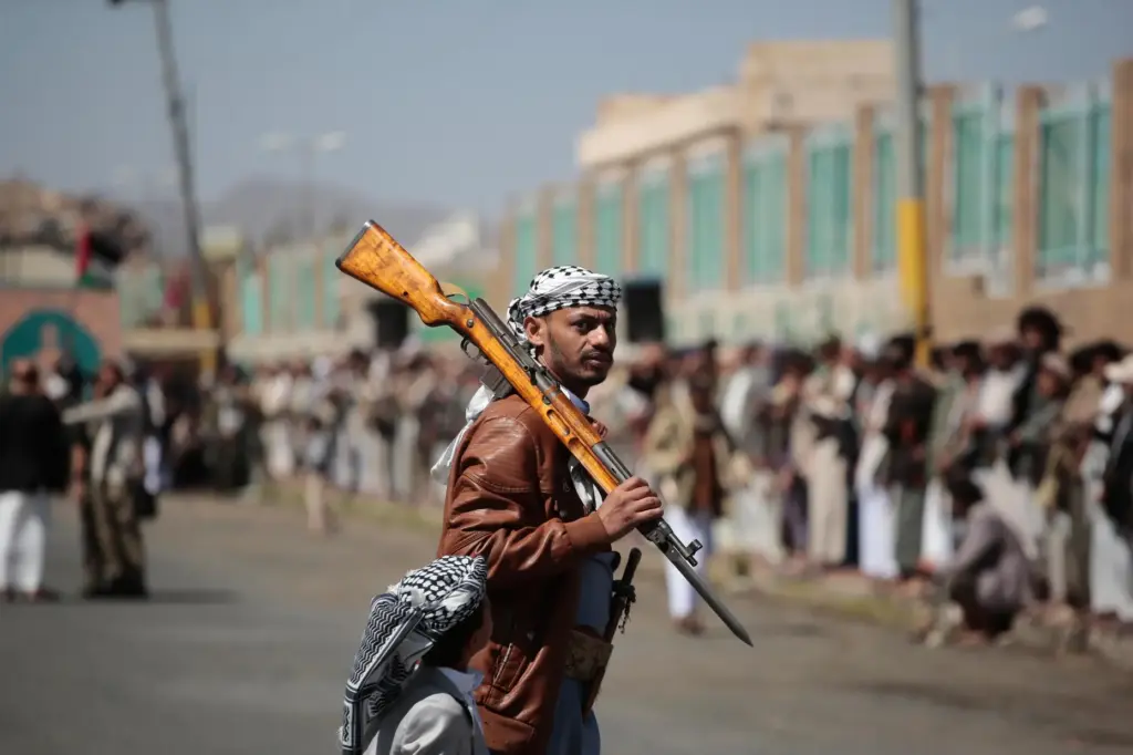 A Houthi supporter carries a rifle while attending an armed...