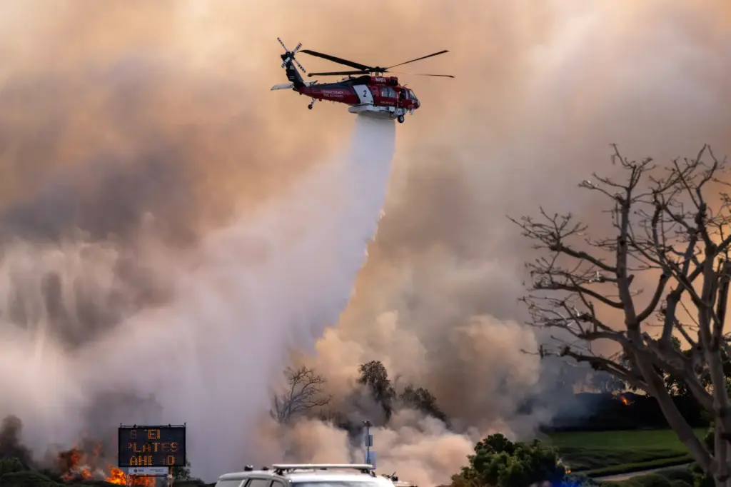 An Orange County Fire Authority helicopter drops water on the...