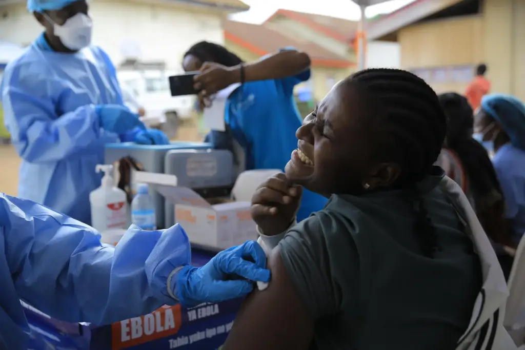 A health care worker reacts while receiving a dose of...