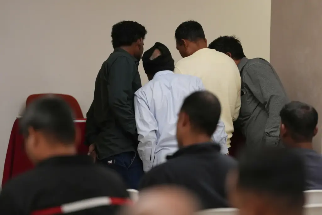 Caddell workers gather in a hotel conference room to wait...