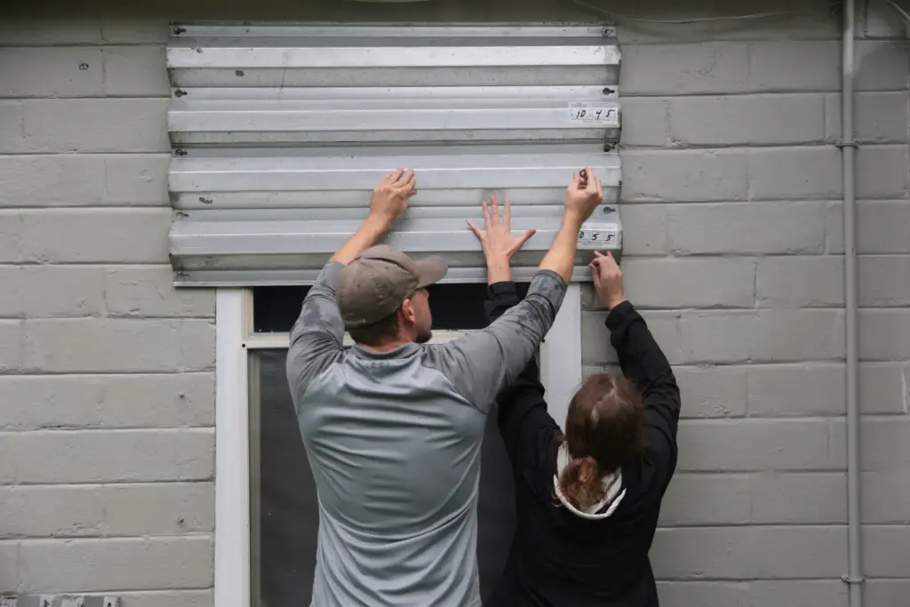 Dan Conley (L) and Suzanna Buchanan put up shutters before...