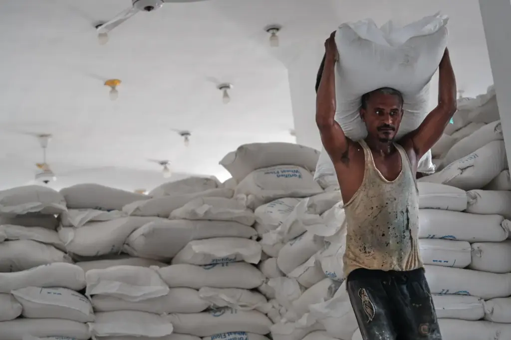 A displaced Yemeni man carries a sack of flour at a food aid warehouse.