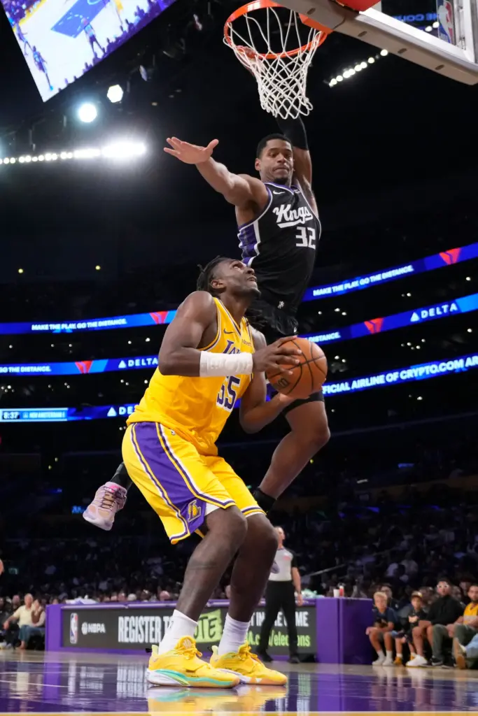 Lakers forward/center Kevon Looney, left, looks to shoot as Sacramento...