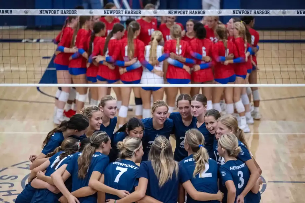 Newport Harbor and Los Alamitos players huddle with their teammates...
