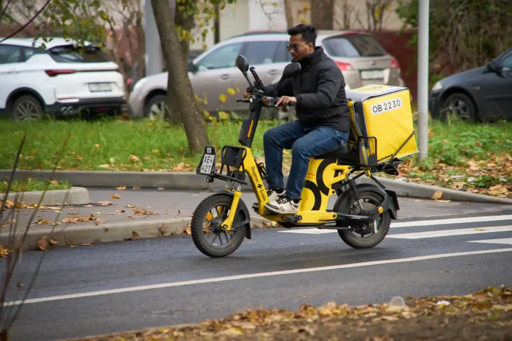 A Yandex food delivery courier rides his scooter in Moscow,...