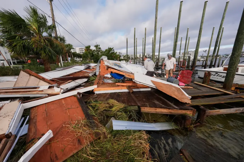People retrieve belongings from a collapsed boat house in the...