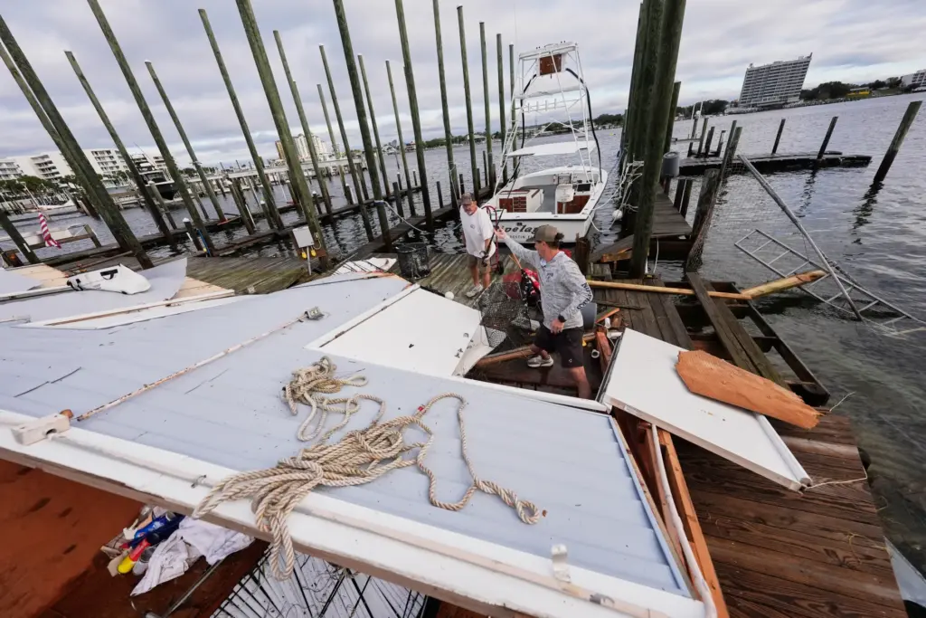 People retrieve belongings from a collapsed boat house in the...