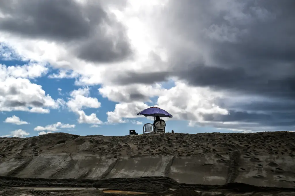 A lifeguard sits atop a new berm as he keeps...