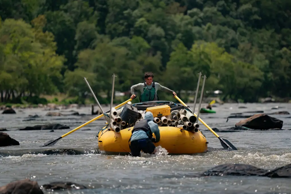 Workers from MountainTrue paddle IPEX PVC pipe they collected from the riverbank.