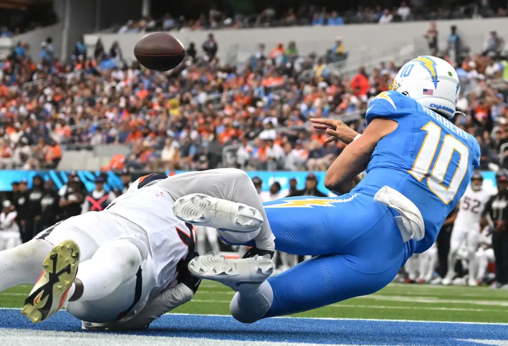 Chargers quarterback Justin Herbert (10) barely gets a pass away...