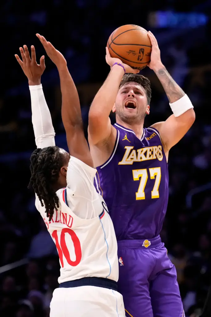 Lakers star Luka Doncic, right, shoots as Clippers guard Darius...
