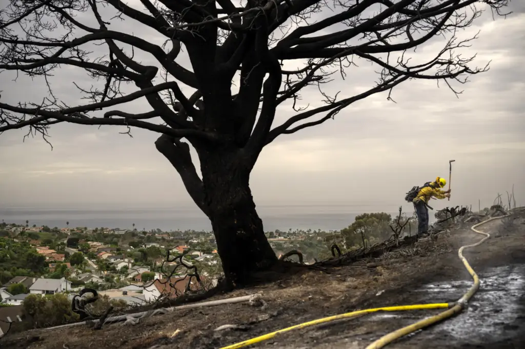 A firefighter works hot spots on a San Juan Capistrano...