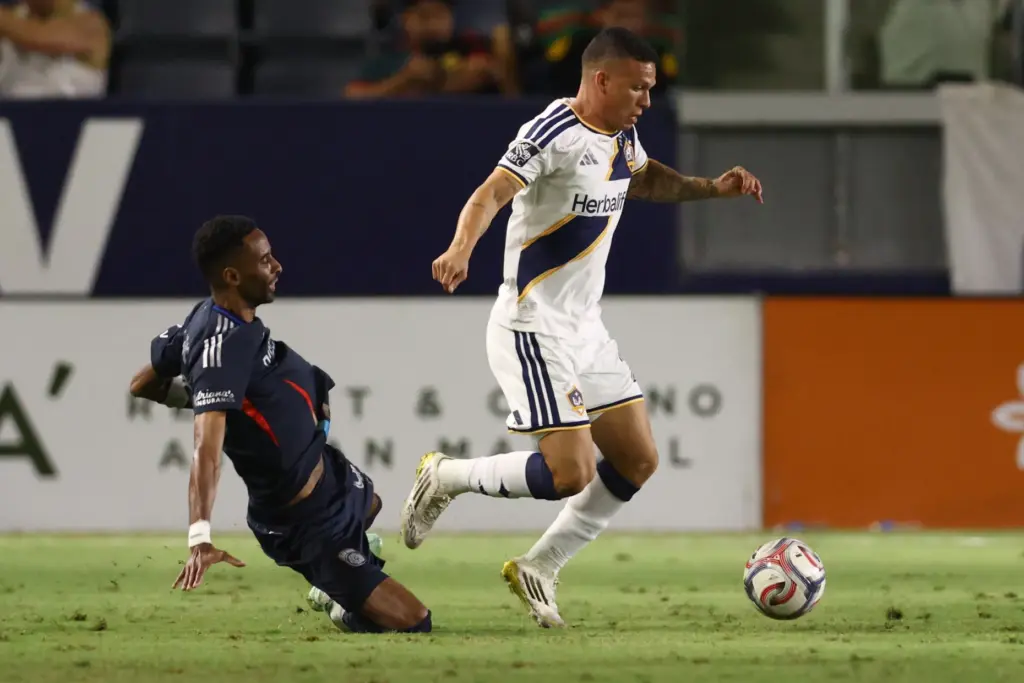 Los Angeles Galaxy defender Lucas Calegari, right, moves the ball...