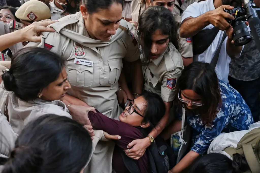 Prominent student leader Neha Bora, center crouching, is detained by...