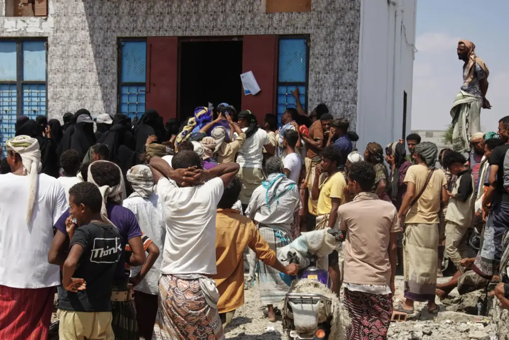 Yemenis displaced by fighting in Taiz gather to receive food aid.