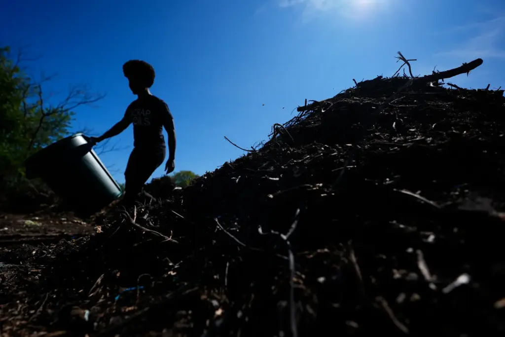 Ricky Blanding, founder of Scrap Soils, drops compostable material at...