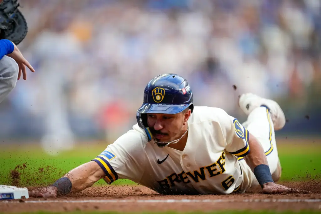The Milwaukee Brewers’ David Hamilton dives back safely on a...