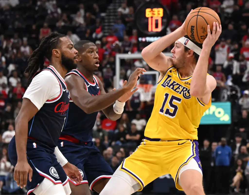 Lakers guard Austin Reaves holds the ball as Clippers guards...