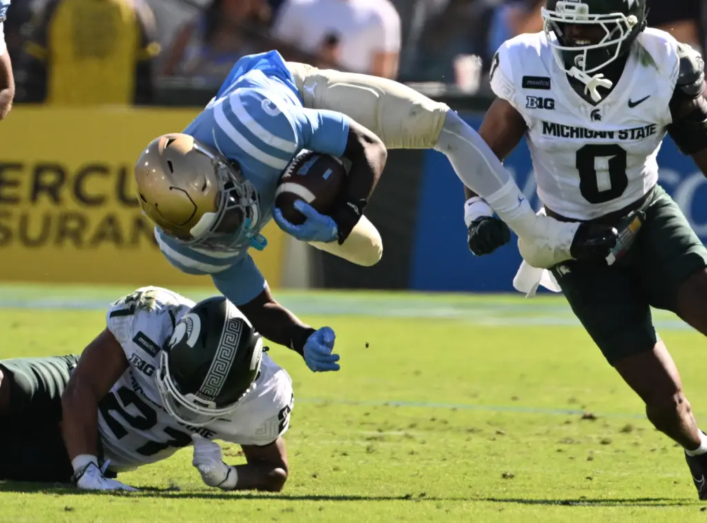 UCLA running back Anthony Woods (6) is upended by Michigan...