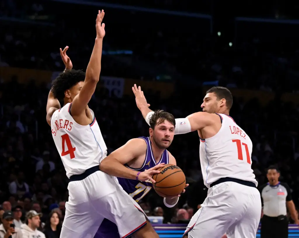 Lakers star Luka Doncic drives between Clippers guard Kobe Sanders,...