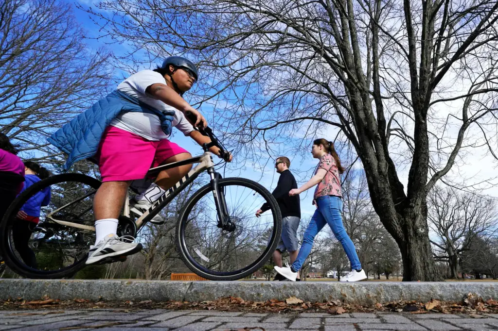 FILE – A bike rider in shorts rolls past a...