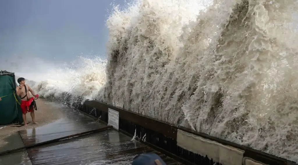 A lifeguard keeps watch as a wave crashes up and...