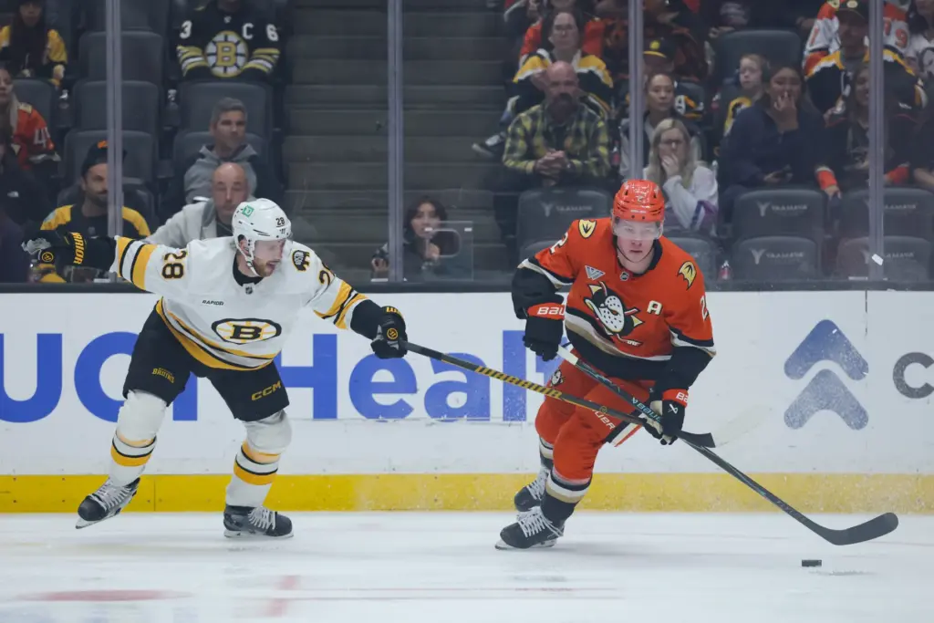 Ducks defenseman Jackson LaCombe, right, and Boston Bruins center Elias...