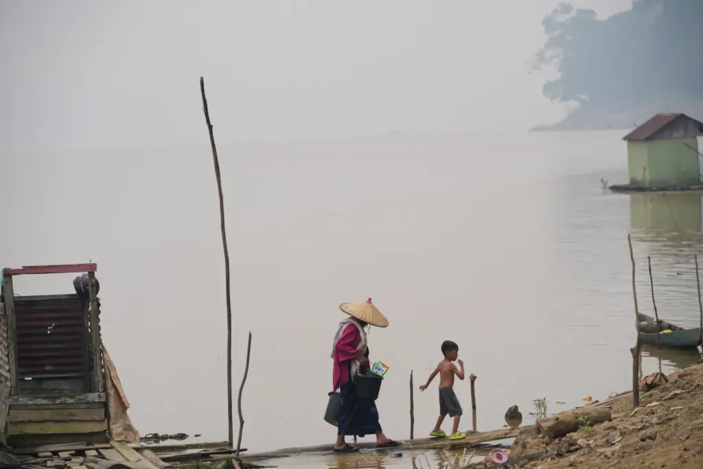 A woman carrying buckets walks with a boy along the...